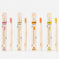 Four adult bamboo toothbrushes with packaging in pink, beige, orange and yellow