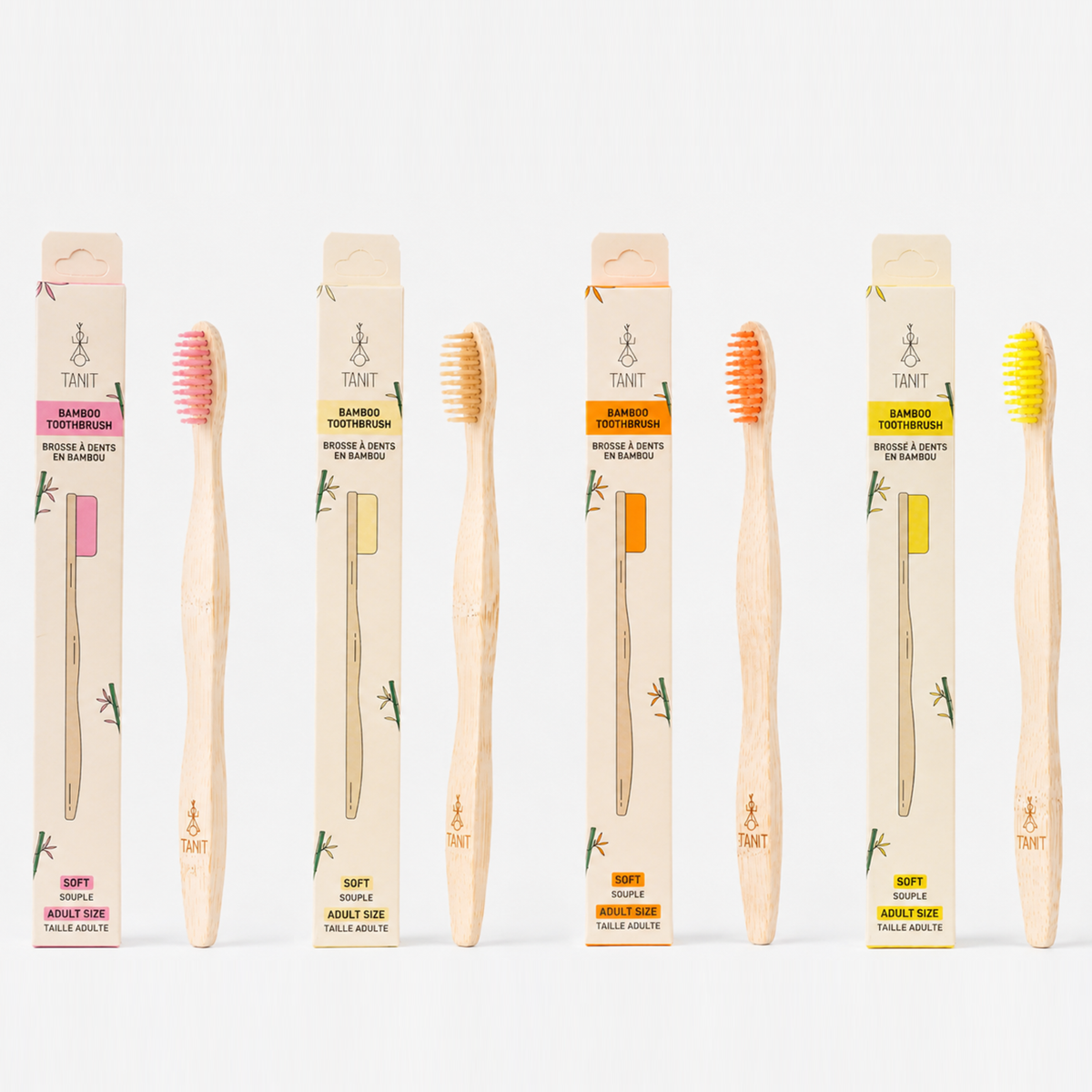 Four adult bamboo toothbrushes with packaging in pink, beige, orange and yellow