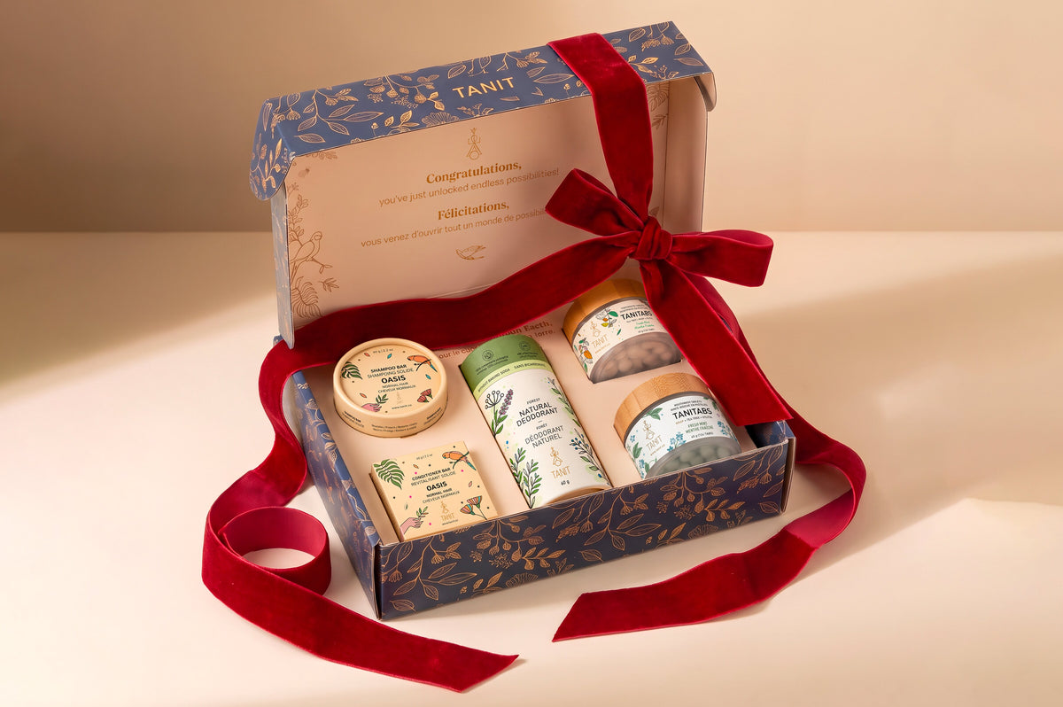 An open TANIT Solid Routine gift box with a shampoo bar, deodorant and Tanitabs, wrapped in burgundy velvet ribbon